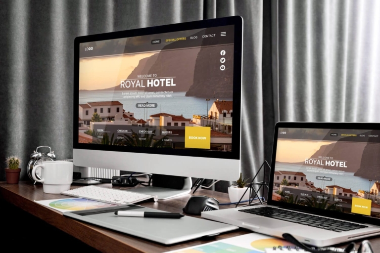 Computer monitors on a desk displaying a generic homepage design as part of a web designer’s portfolio.
