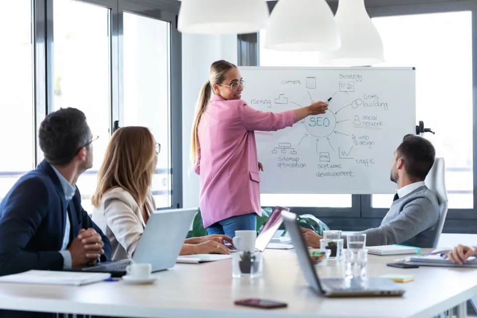 A businesswoman explaining a project at a whiteboard.